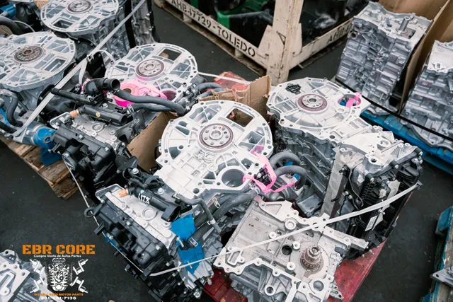 Car engines piled in a warehouse, some marked with pink tape, close up shot.
